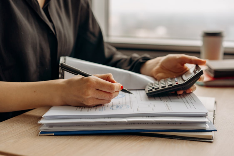 business owner reviewing financial paperwork with a laptop and calculator