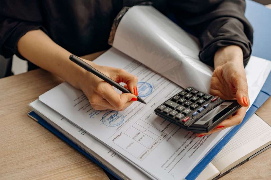 accountant reviewing payroll reports with calculator and financial paperwork