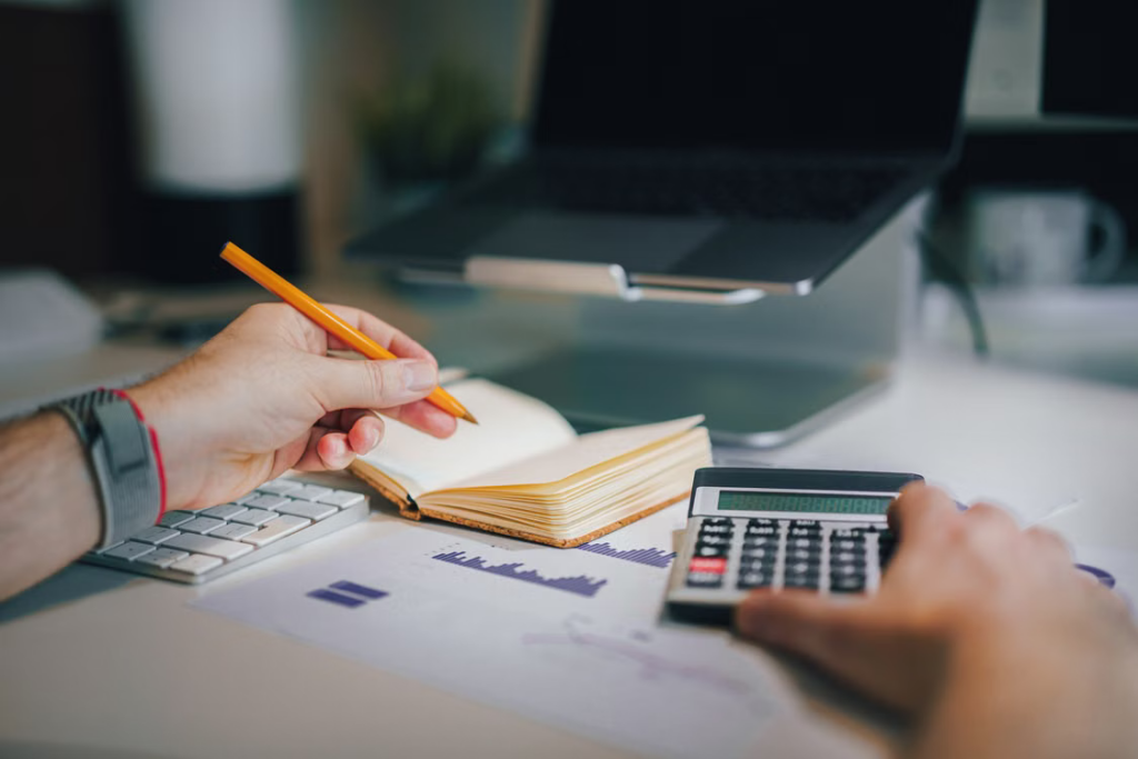 Business owner organizing financial documents with a laptop and calculator